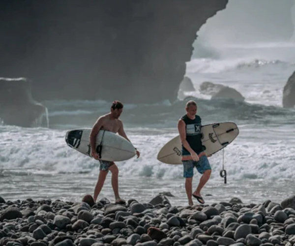 surfers walking on the beach holding their surfboards